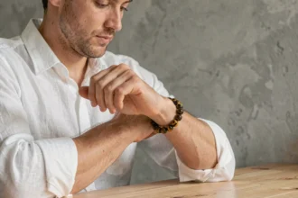 Homme portant un bracelet œil du tigre en pierre naturelle avec une chemise en lin blanc, style minimaliste et élégant