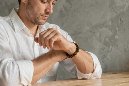Homme portant un bracelet œil du tigre en pierre naturelle avec une chemise en lin blanc, style minimaliste et élégant