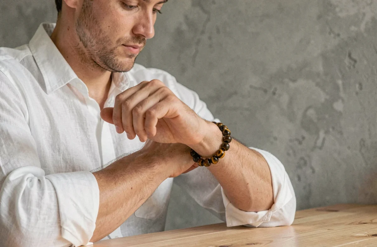 Homme portant un bracelet œil du tigre en pierre naturelle avec une chemise en lin blanc, style minimaliste et élégant